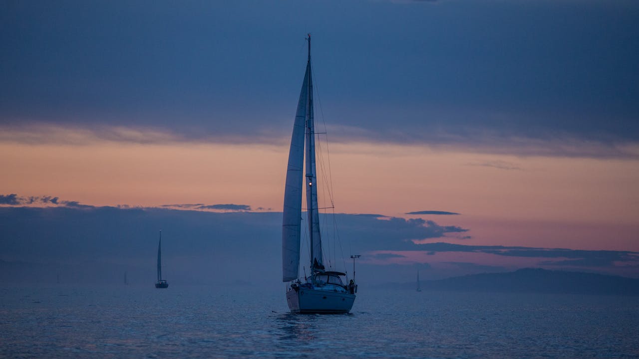 A peaceful sailboat navigates the calm Norwegian waters during a stunning sunset.