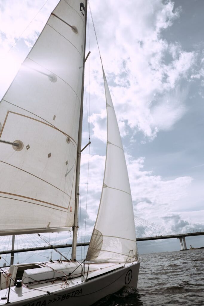 A sailboat gracefully glides across the open sea under bright, sunny skies, offering a sense of freedom and adventure.